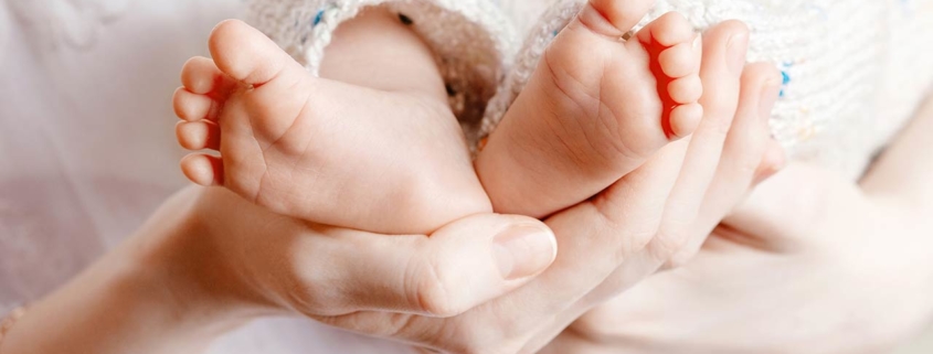 Photo of a tiny Newborn Baby's feet on female Heart Shaped hands