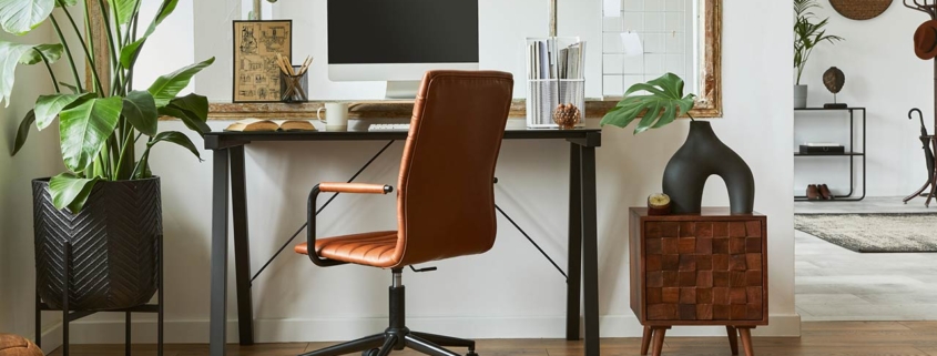 Creative composition of modern masculine home office workspace interior with black industrial desk, brown leather armchair, pc and stylish personal accessories