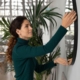Close up smiling woman hanging or fixing mirror on wall