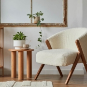 Stylish compositon of modern living room interior with frotte armchair, wooden commode, side table and elegant home accessories