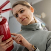 A woman checks the fire extinguisher expiration date at home