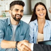 Real estate agent with couple shaking hands closing a deal and signing a contract