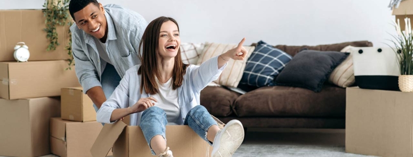 Happy mixed race young family couple, bought their own house, they having fun on moving day