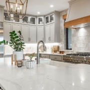 Large kithchen with white countertops, grey cabinets, stainless appliances, large white porcelain double sink farmhouse style