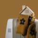 Wrapped in a warm scarf, a symbolic wooden house stands on an electric radiator