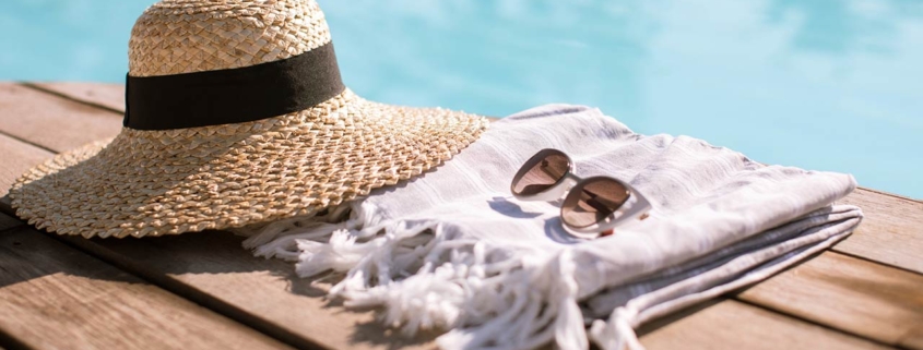 Sunglasses and straw hat on the wooden floor at the pool