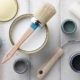 Paint brush, sponge roller, paints, waxes and other painting or decorating supplies on white wooden planks