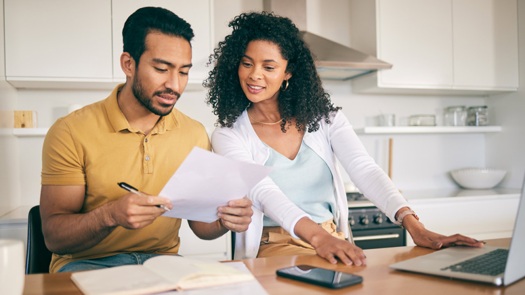 Couple reviewing financial documents at a kitchen counter