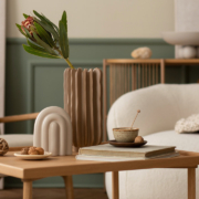 living room with boucle sofa, wooden coffee table, books, stylish sculpture, vase with leaves and personal accessories