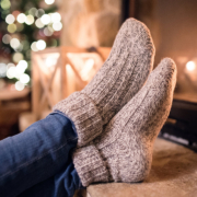 Feet of unrecognizable woman in woollen socks by the Christmas fireplace