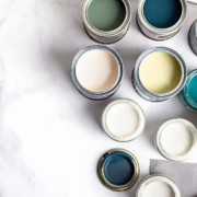 Tiny sample paint cans during house renovation, process of choosing paint for the walls, different green and beige colors, color charts on marble background