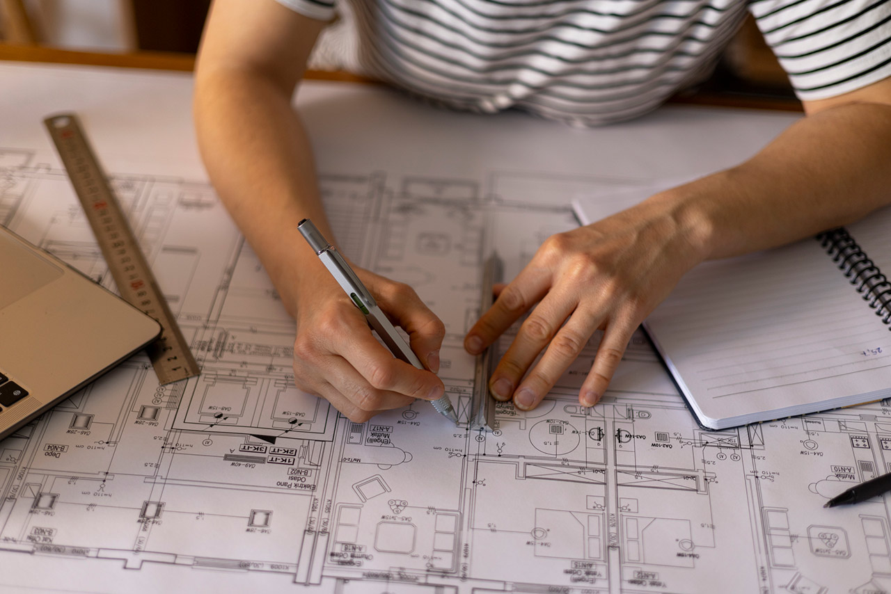 Architect working on a construction project, drawing blueprints using a ruler and a technical pen
