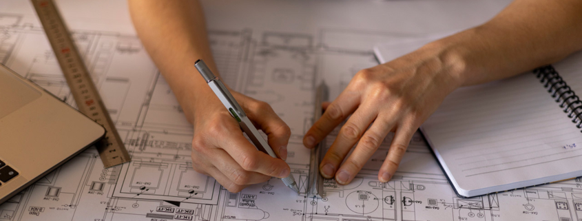 Architect working on a construction project, drawing blueprints using a ruler and a technical pen