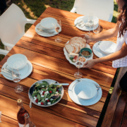 Top view of woman setting food on wooden table for housewarming party.