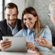 Happy couple using tablet while having a meeting with their real estate agent in the office